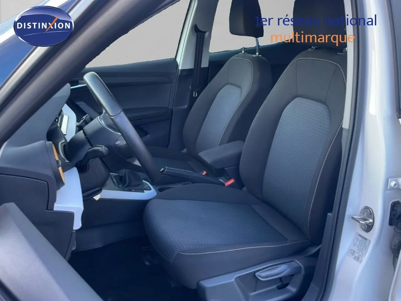 Vue intérieure côté conducteur du SEAT Arona blanc avec sièges tissu gris et volant cuir multifonction.