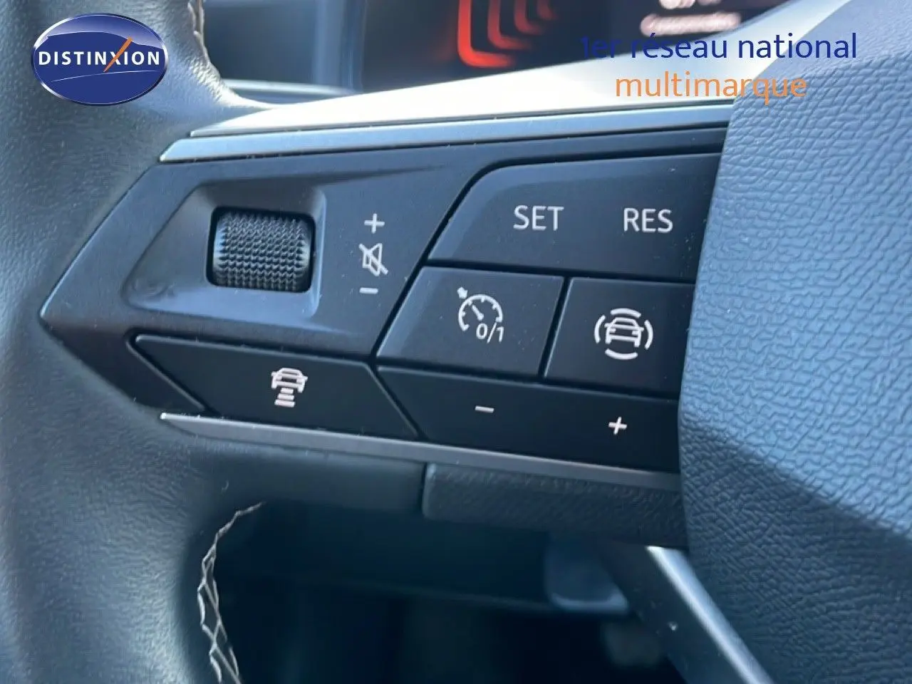 Gros plan sur les commandes au volant d'un SEAT Arona blanc toit gris, montrant les boutons de régulateur de vitesse et d'assistance.