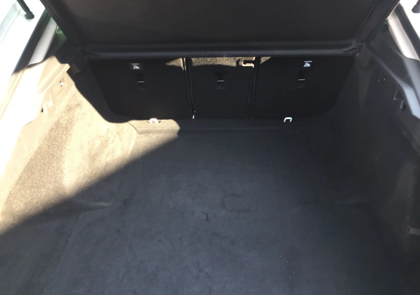 Coffre spacieux de l'Opel Insignia Grand Sport blanc nacré vu de l'arrière avec banquette arrière rabattable noire.