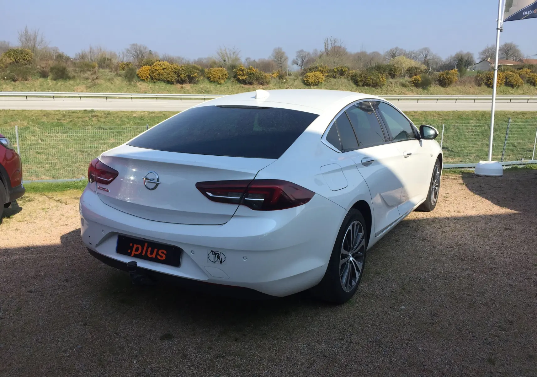 Opel Insignia Grand Sport blanc nacré vue 3/4 arrière droit, avec vitres teintées et jantes alliage.