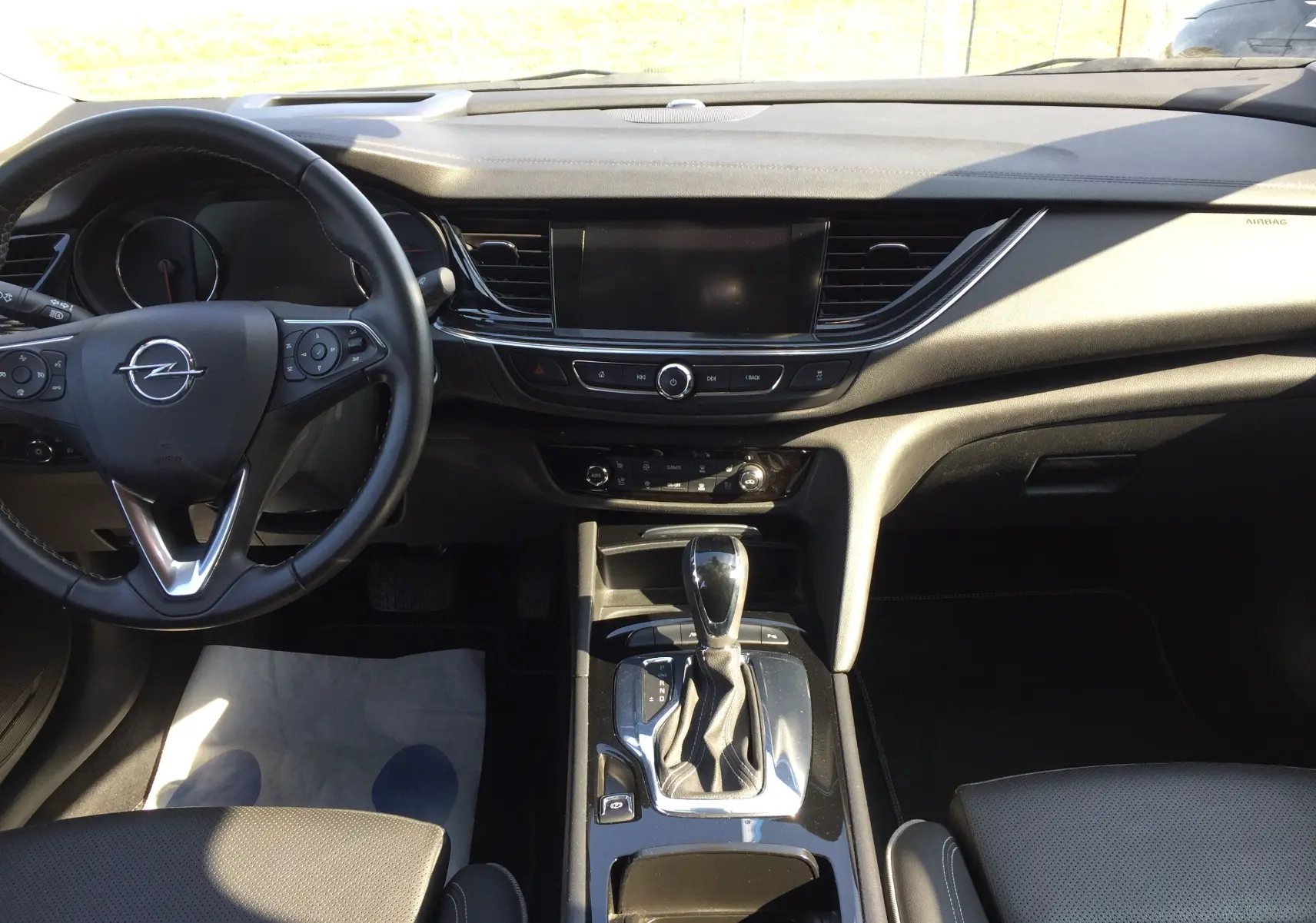 Intérieur noir de l'Opel Insignia Grand Sport 2017, vue de face sur le tableau de bord et la console centrale avec boîte auto.