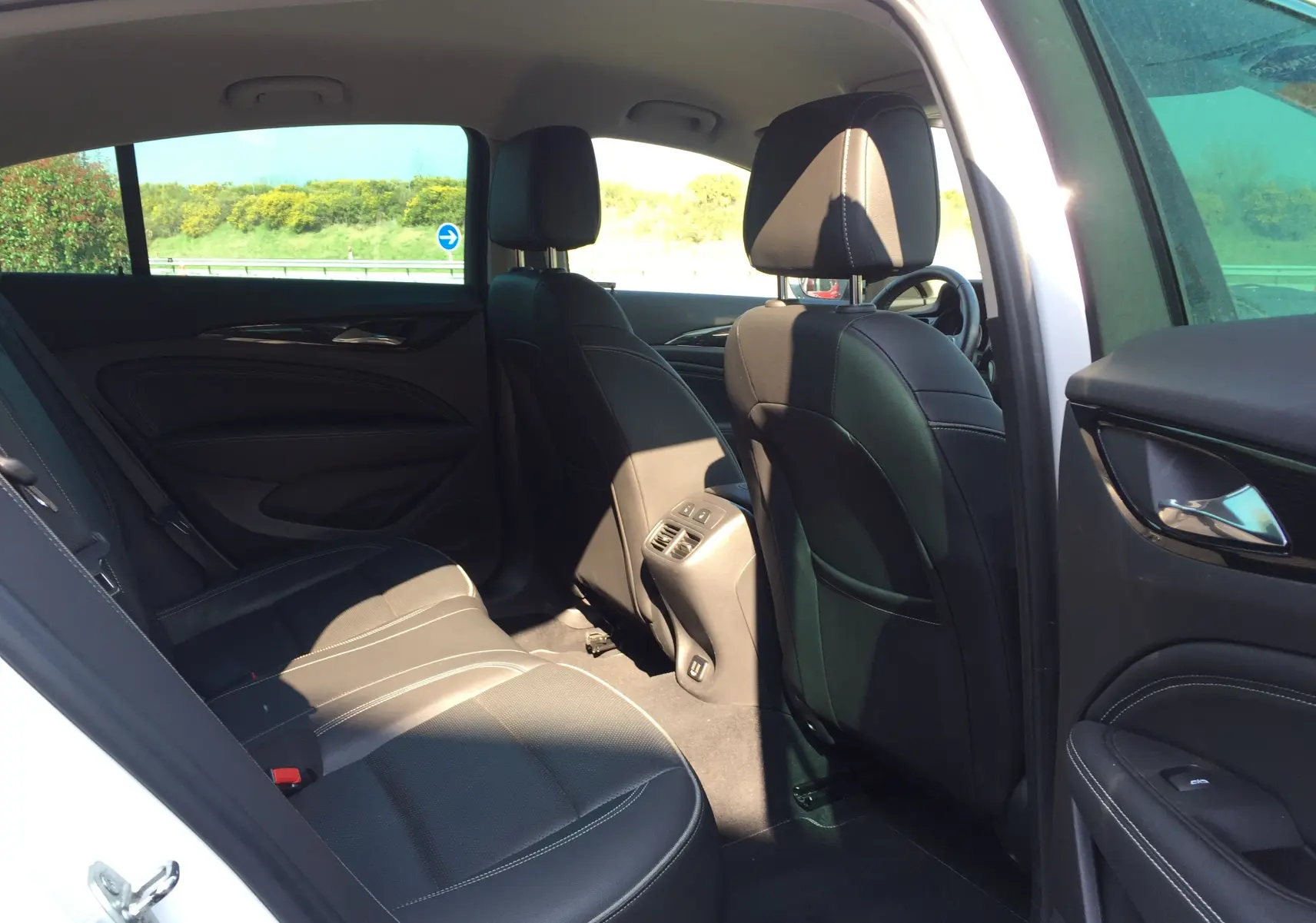 Vue intérieure côté droit arrière d'une Opel Insignia Grand Sport blanc nacré, sièges cuir noirs et finitions modernes.