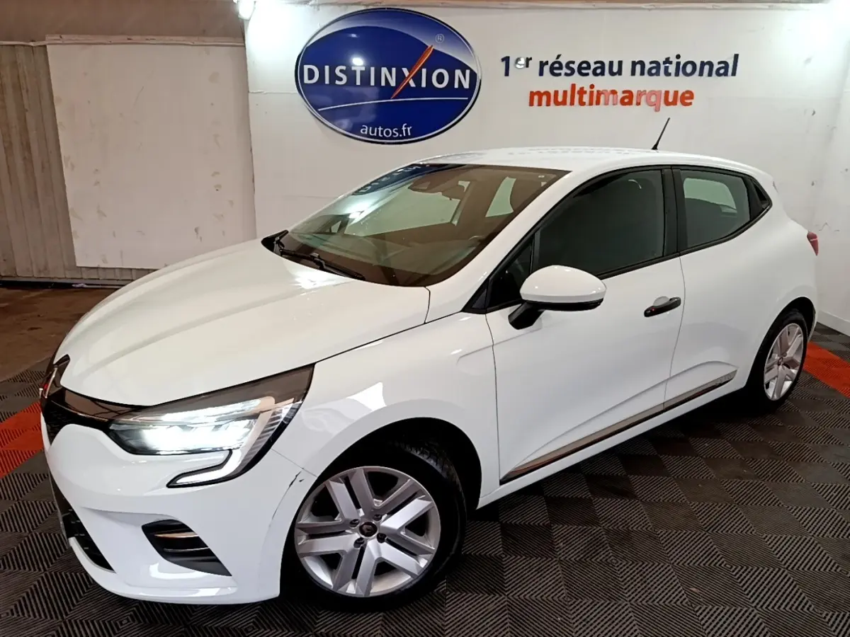 Renault Clio Business blanc vue 3/4 avant droit avec phares LED allumés dans un showroom intérieur.