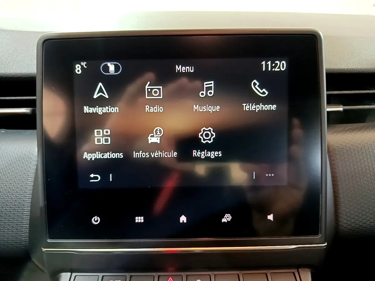 Écran tactile central de la Renault Clio Business blanc, affichant le menu principal avec navigation et réglages.