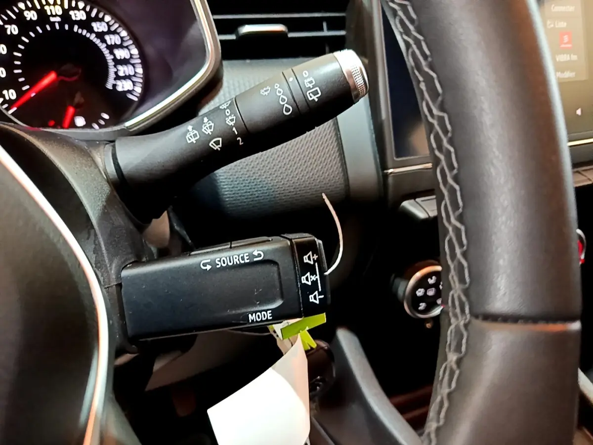 Gros plan sur les commandes au volant et le tableau de bord de la Renault Clio Business blanche, avec affichage numérique visible.