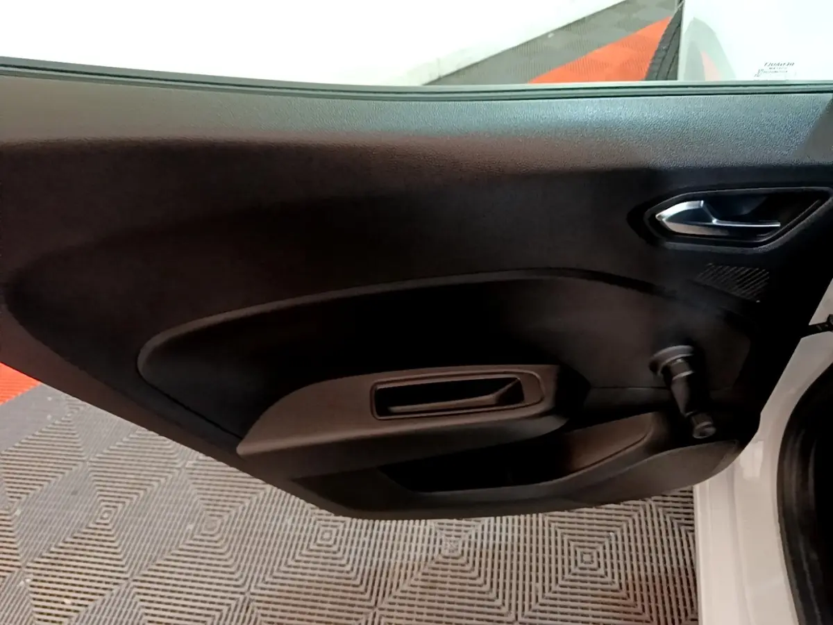 Vue intérieure de la porte avant droite blanche d'une Renault Clio Business SCe 65 avec poignée et manivelle de vitre.