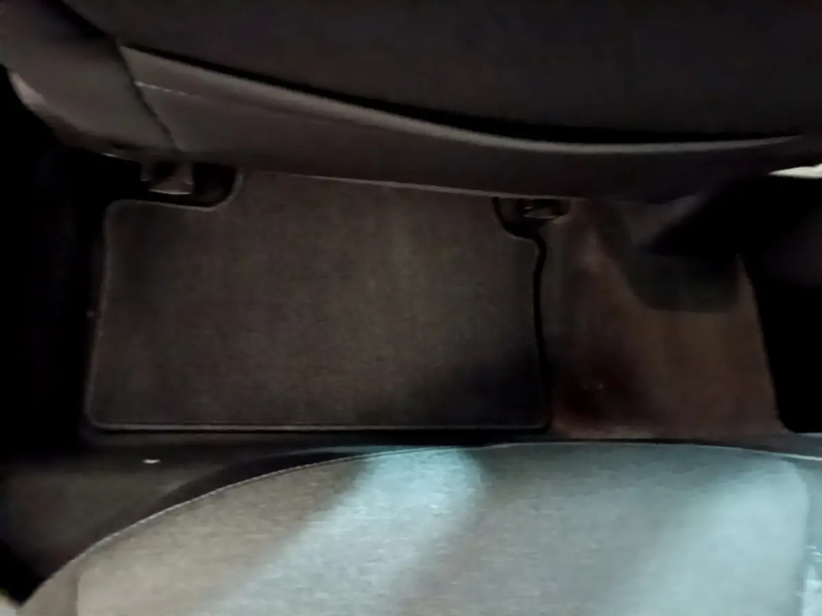 Vue rapprochée du tapis de sol noir côté passager arrière d’une Renault Clio blanche, version Business 2021.