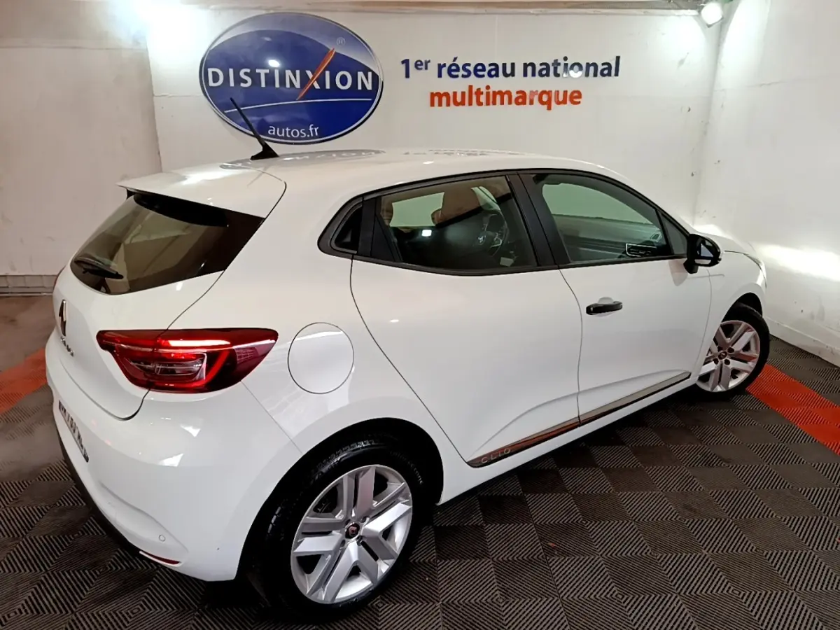 Renault Clio Business blanche vue 3/4 arrière droit en intérieur avec jantes alliage et feux LED allumés.