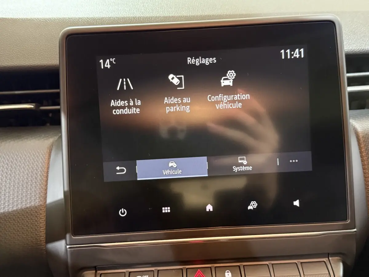 Écran tactile central de la Renault Clio Business blanc, affichant les réglages d’aides à la conduite et parking.