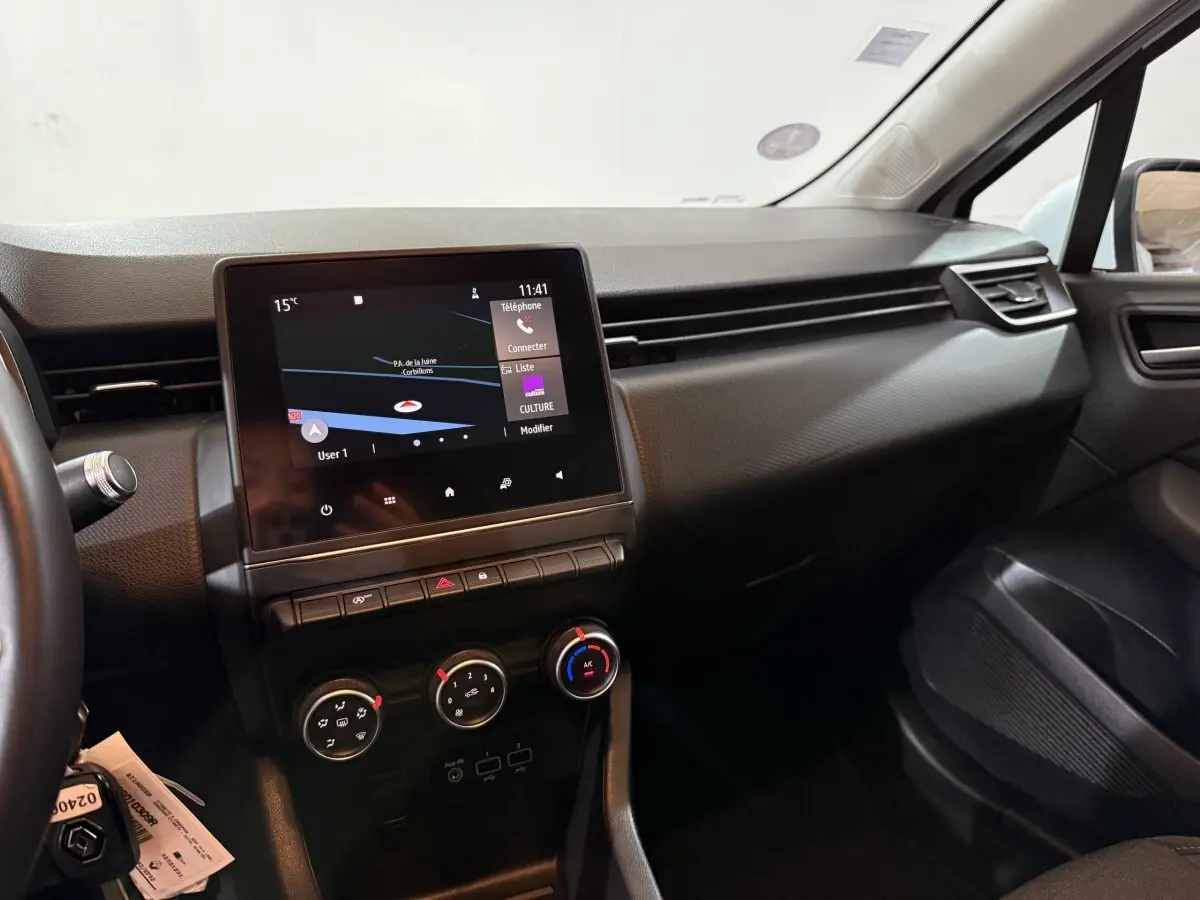 Vue intérieure côté passager de la Renault Clio Business blanche de 2020, avec écran tactile central et commandes de climatisation.