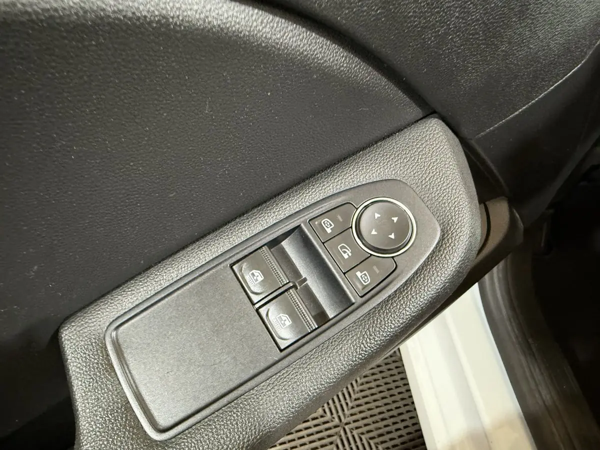 Gros plan sur la commande des vitres électriques côté conducteur d’une Renault Clio Business blanche, intérieur noir.