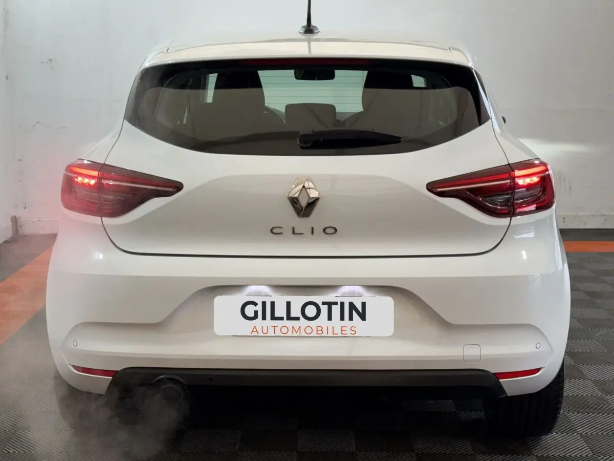 Vue arrière d'une Renault Clio Business blanche de 2020 avec feux arrière allumés et logo centré.