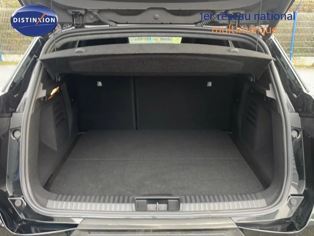 Coffre ouvert vu de l'arrière d'une Renault SYMBIOZ noire étoile métal, montrant un espace de chargement vide et propre.