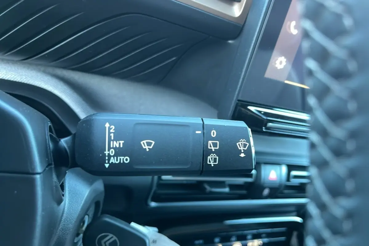 Gros plan sur la commande des essuie-glaces à gauche du volant dans l’habitacle noir du Citroën C3 Aircross 2025.