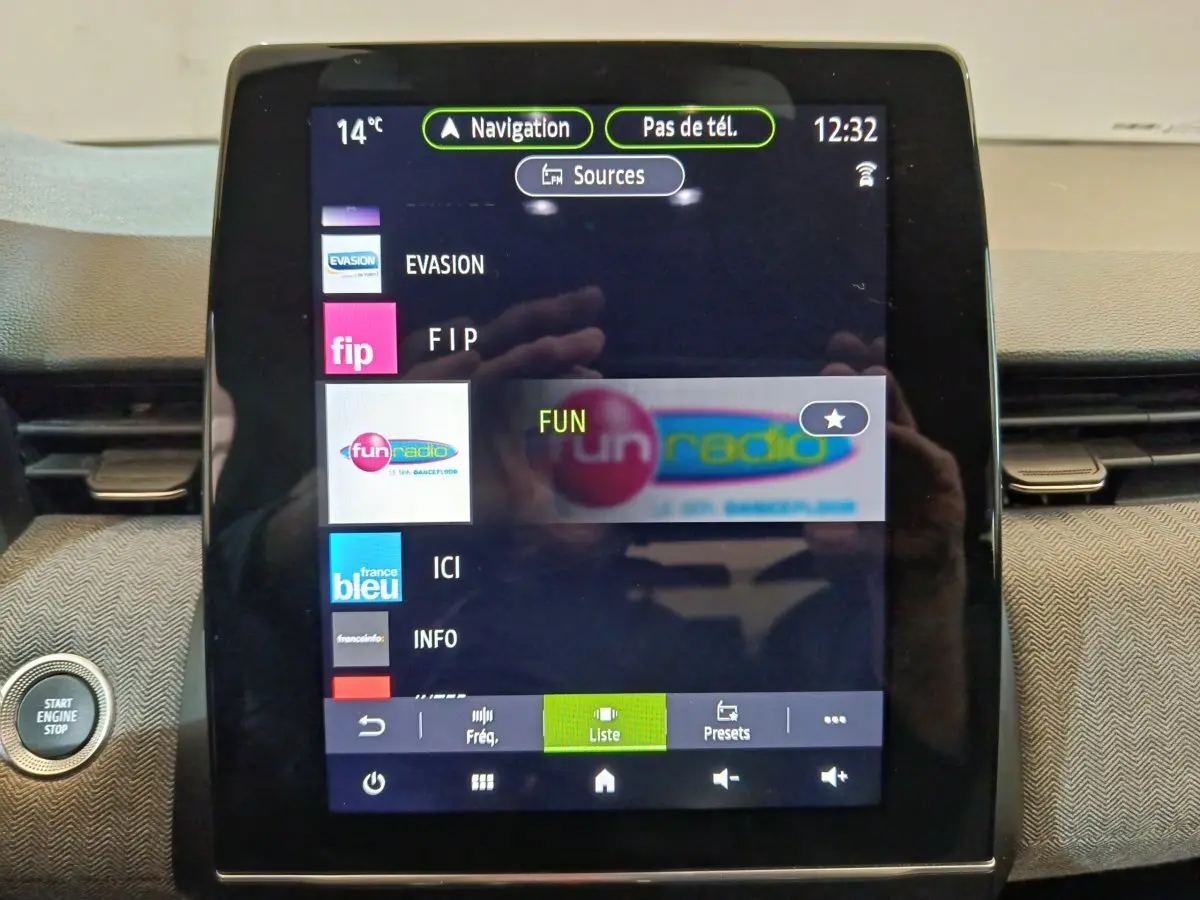 Écran tactile central de la Renault Clio Techno TCe 90 2024 affichant les stations radio, avec bouton démarrage visible à gauche.