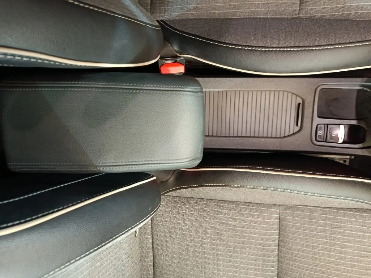 Vue plongeante sur la console centrale et les sièges noirs avec surpiqûres blanches de la Renault Clio Techno TCe 90 rouge 2024.