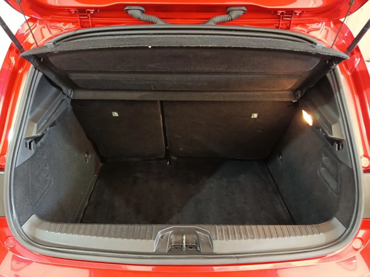 Coffre ouvert vu de l'arrière d'une Renault Clio Techno TCe 90 rouge, montrant l'espace de chargement vide.