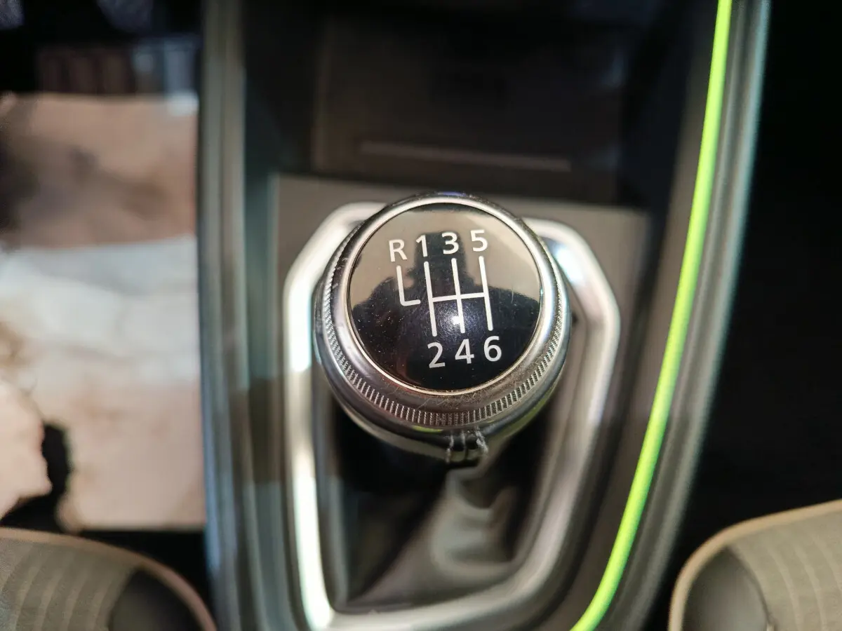 Gros plan sur le levier de vitesses manuel noir de la Renault Clio Techno TCe 90, entouré de garniture grise et éclairage vert.