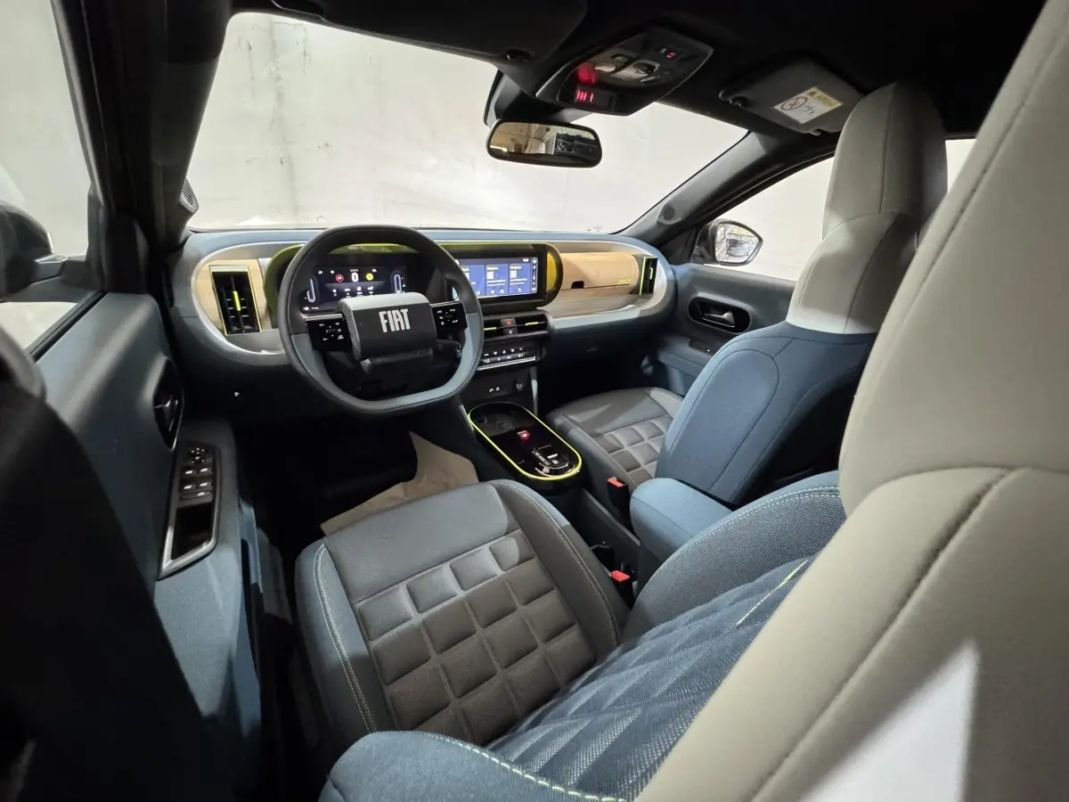 Vue intérieure avant droite de la Fiat Grande Panda marron 2025, tableau de bord moderne avec écran tactile et volant cuir.