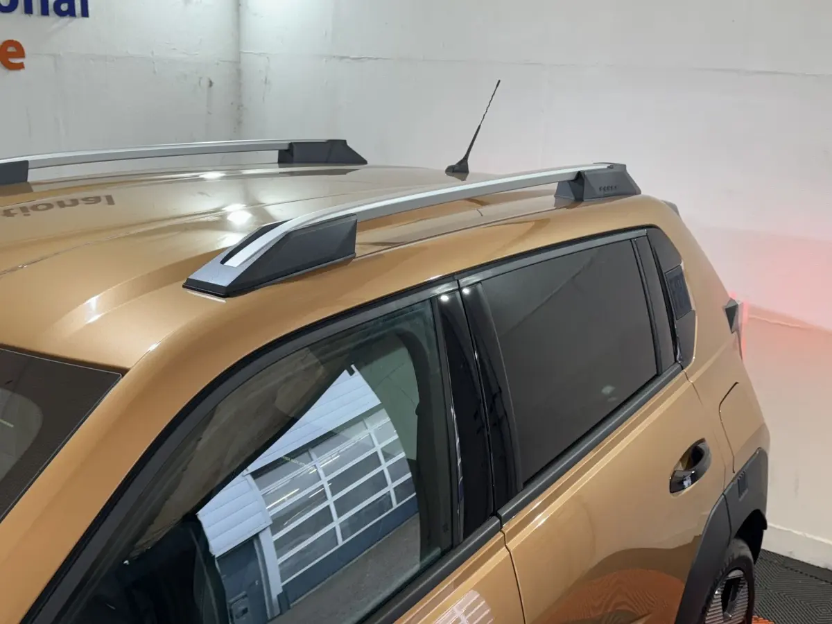 Vue de côté droit arrière sur la FIAT Grande Panda marron 2025 avec barres de toit et vitres teintées.