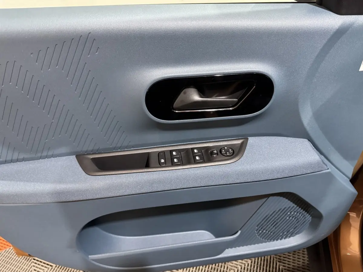 Gros plan sur la porte avant gauche marron de la Fiat Grande Panda 2025 avec commandes électriques et poignée noire.