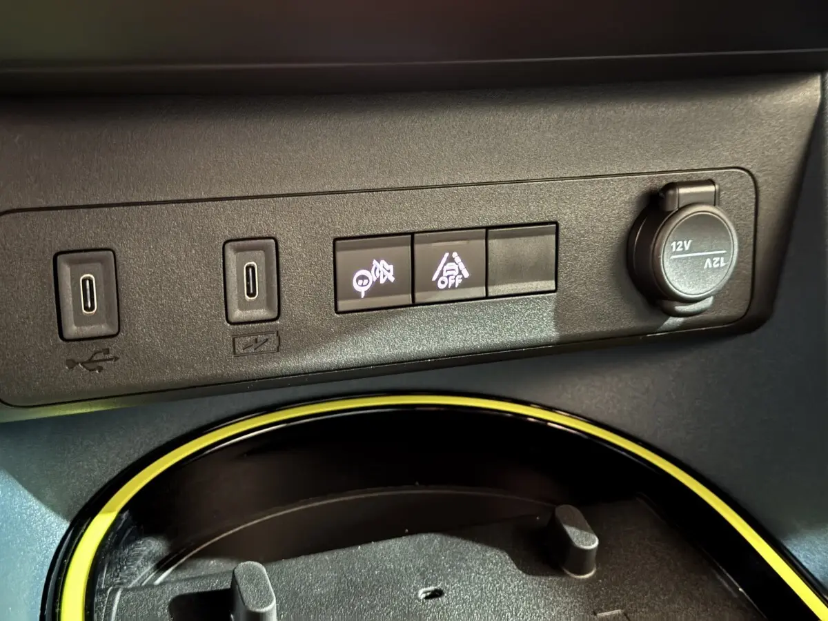 Gros plan sur la console centrale de la Fiat Grande Panda marron, montrant ports USB, boutons d’aide à la conduite et prise 12V.