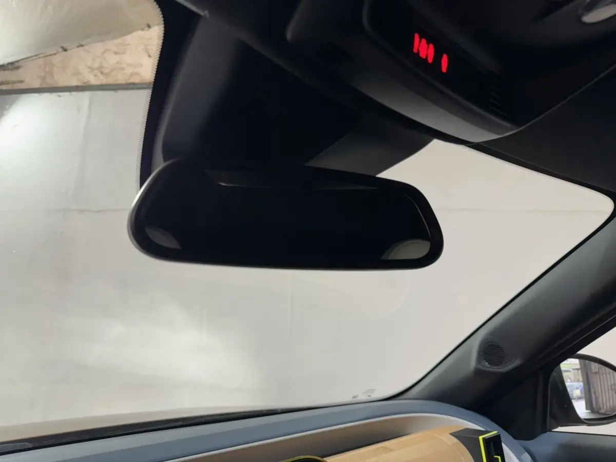 Rétroviseur intérieur vu de l'habitacle d'une Fiat Grande Panda 2025, avec tableau de bord marron visible côté droit.
