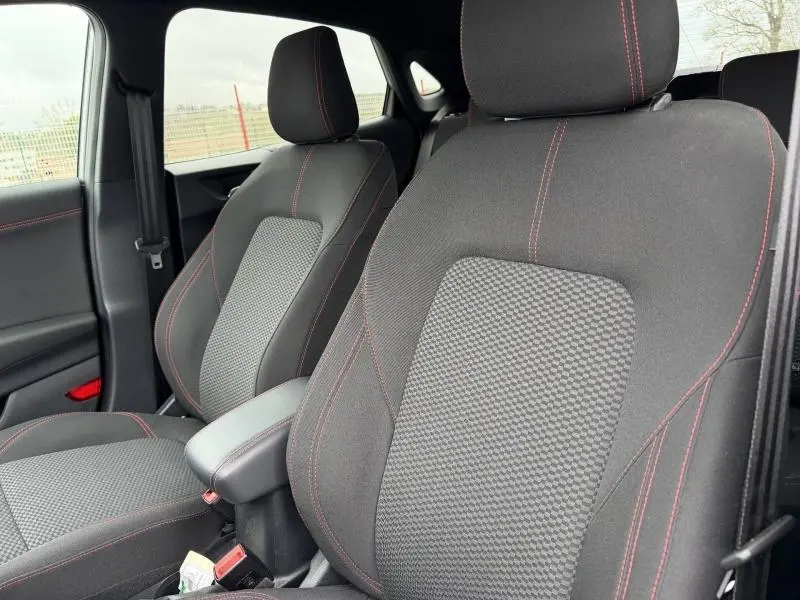 Gros plan sur les sièges avant sport noirs avec surpiqûres rouges du Ford Puma 2024, intérieur côté conducteur et passager.