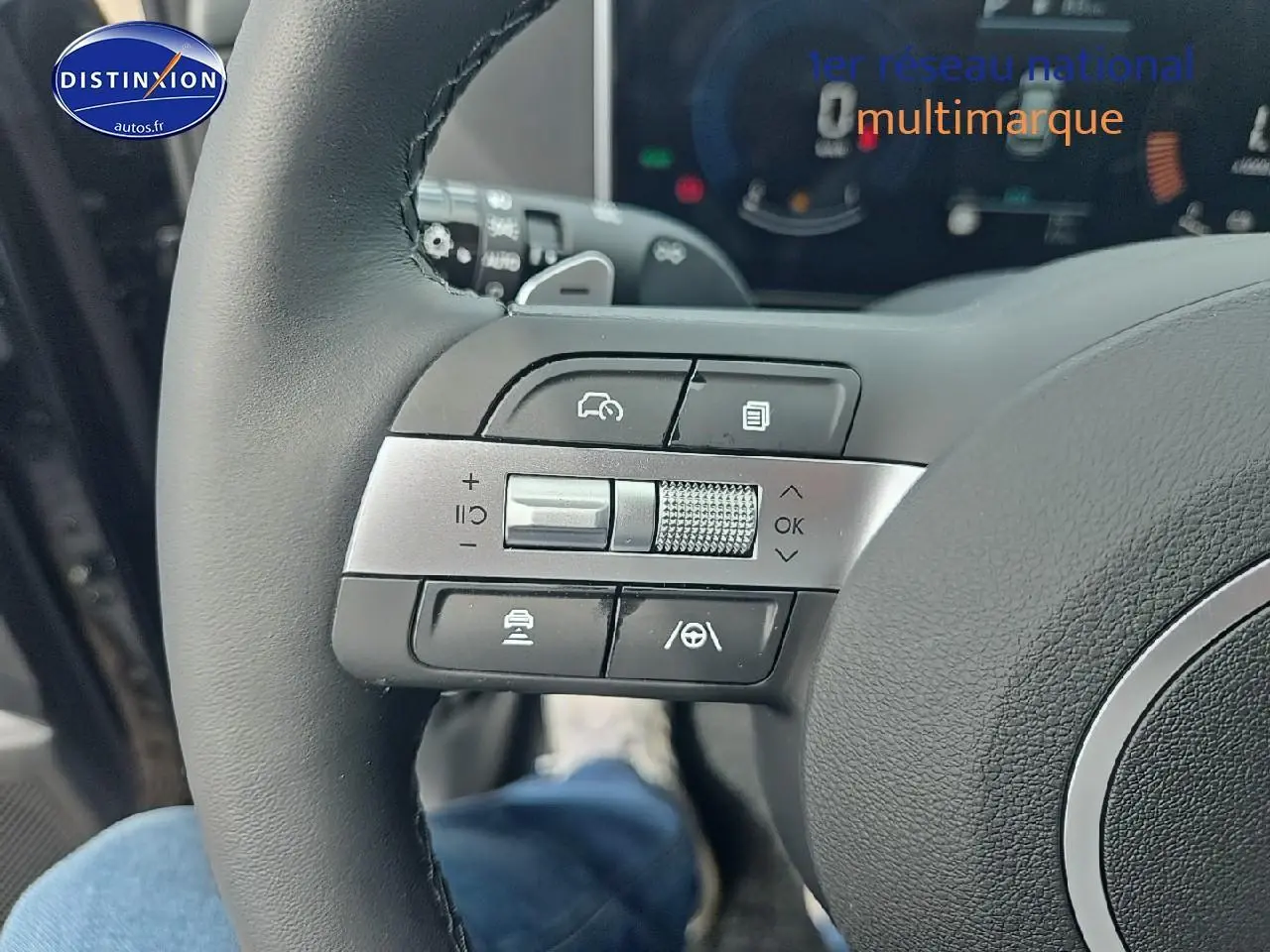 Gros plan sur les commandes au volant cuir du Hyundai Tucson noir abysse hybride 2025, avec tableau de bord numérique en arrière-plan.