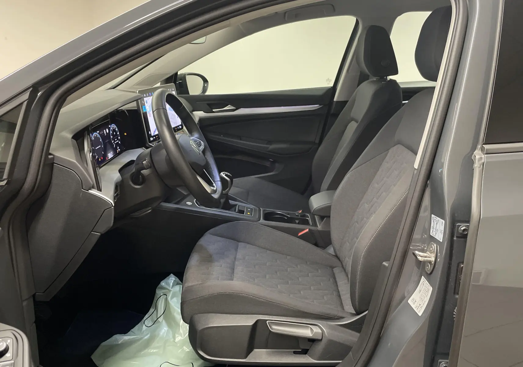 Intérieur avant droit de la Volkswagen Golf 2024 gris dauphin, sièges tissu gris et tableau de bord numérique.