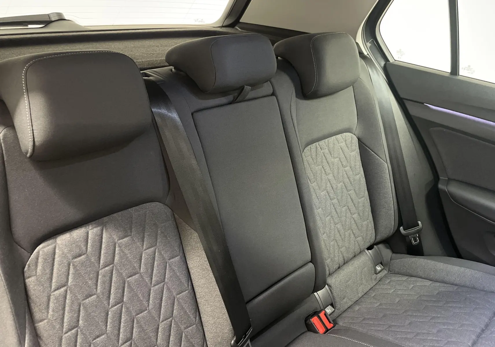 Banquette arrière en tissu gris avec motifs géométriques et appuie-têtes dans une Volkswagen Golf 2024 vue côté droit.