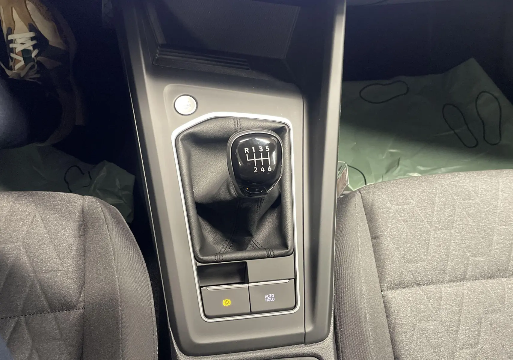 Le levier de vitesses manuel noir de la Volkswagen Golf 2024 vu de dessus entre les sièges gris.