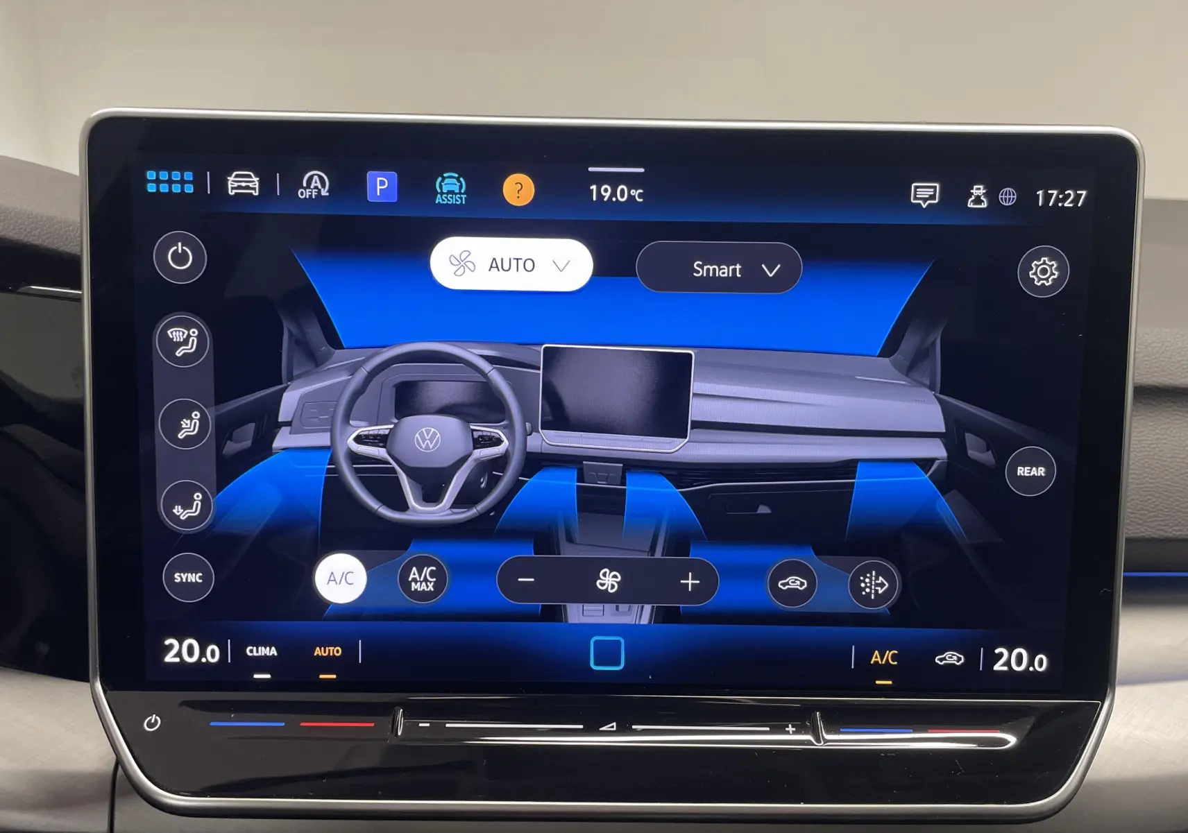 Vue de face du tableau de bord numérique de la Volkswagen Golf 2024 Gris Dauphin, avec écran tactile central et commandes climatisation.