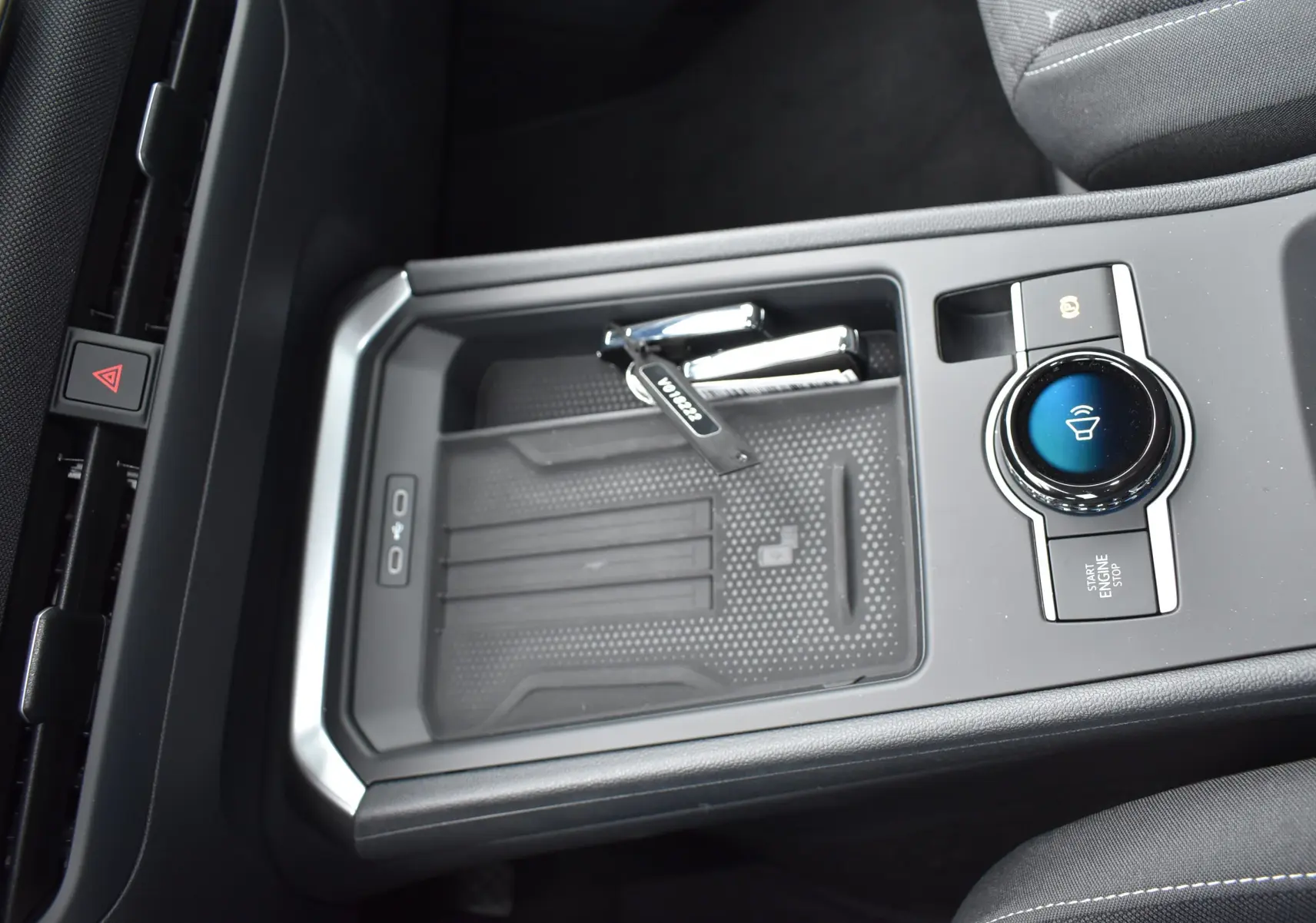 Gros plan sur la console centrale noire du Volkswagen T-Roc 2025 avec bouton start/stop et clé posée.