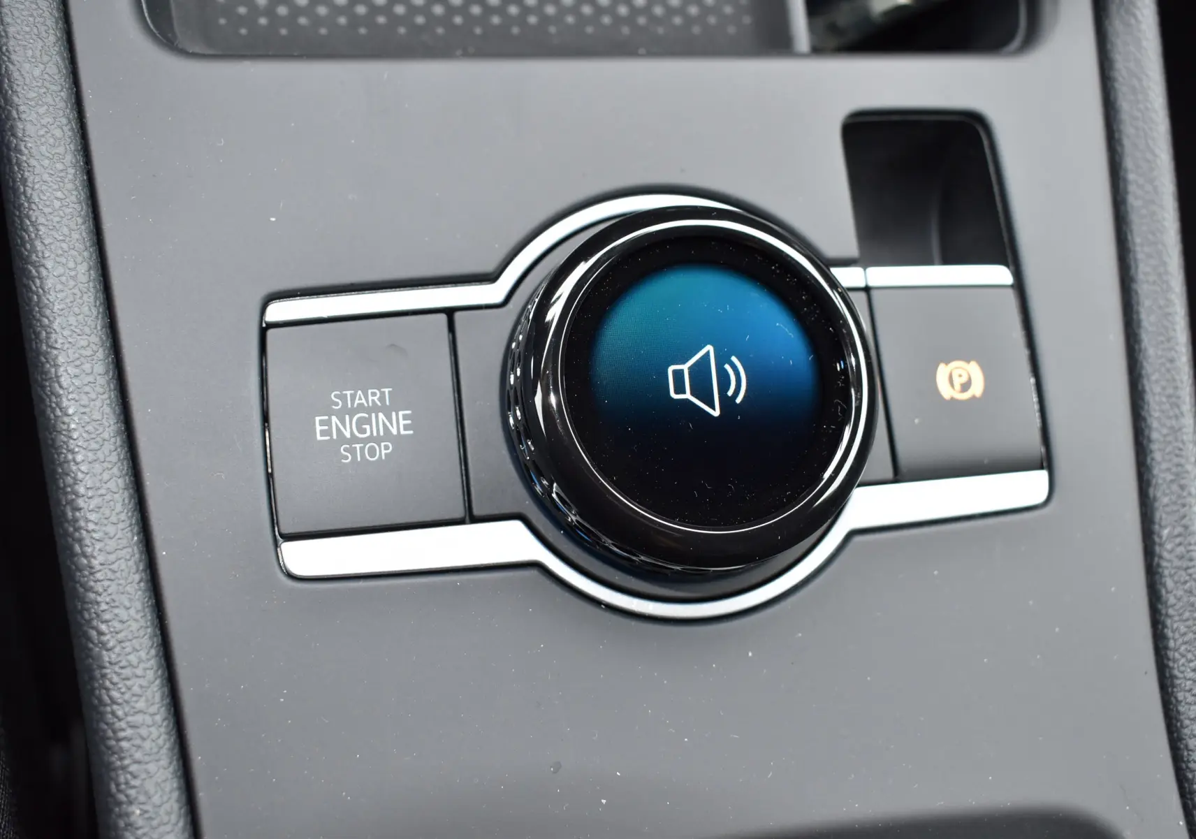 Détail du bouton de commande audio et démarrage sans clé sur la console centrale du Volkswagen T-Roc blanc 2025.