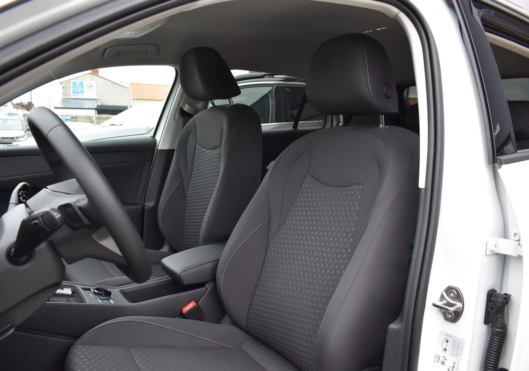 Vue intérieure côté conducteur du Volkswagen T-Roc blanc 2025, sièges tissu gris avec coutures contrastées.