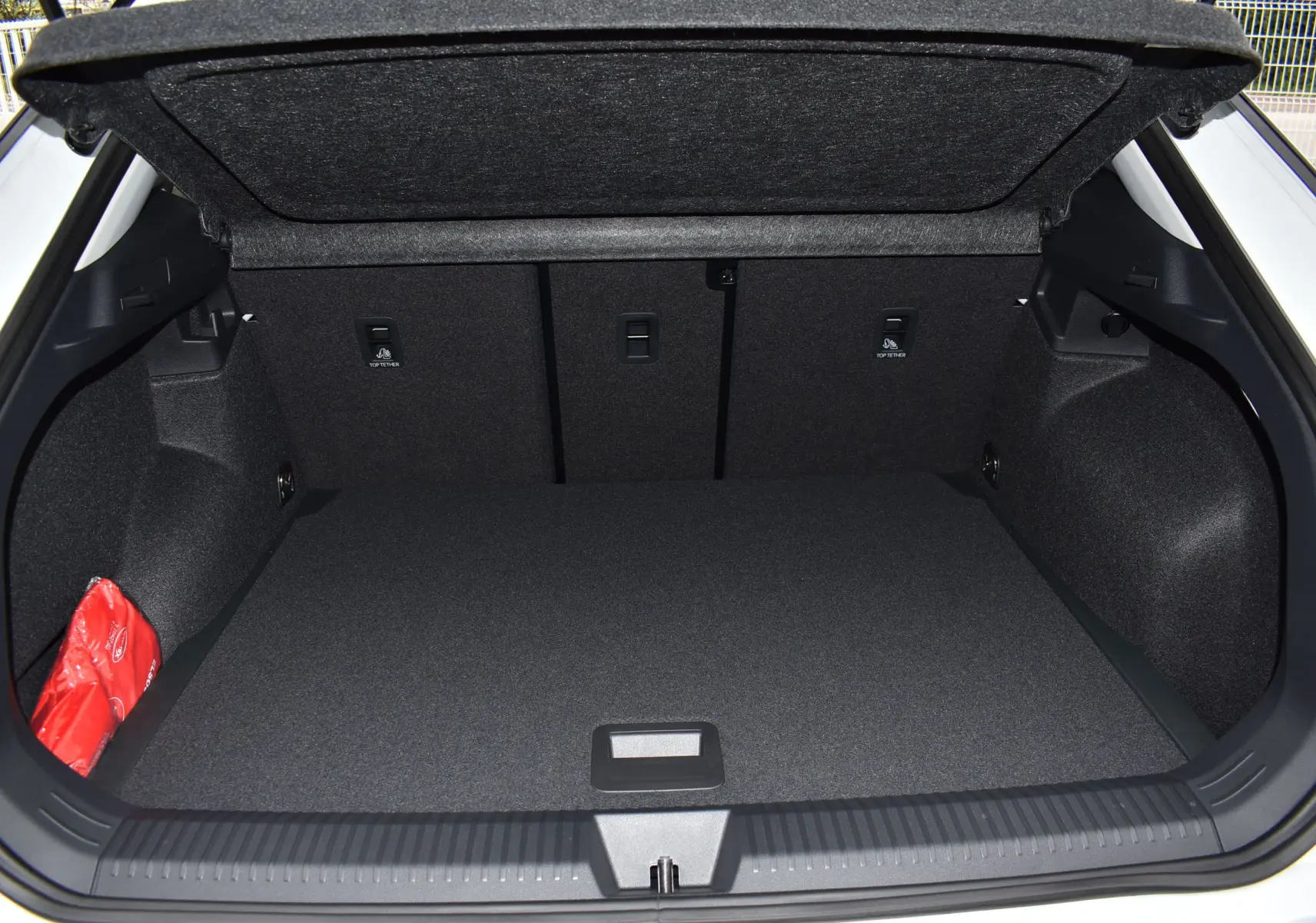 Coffre ouvert du Volkswagen T-Roc blanc, vue arrière montrant l'espace de chargement et cache-bagages rigide.