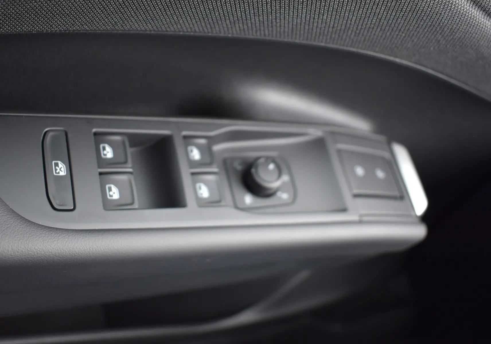 Gros plan sur les commandes des vitres et rétroviseurs côté conducteur du Volkswagen T-Roc blanc, intérieur noir.