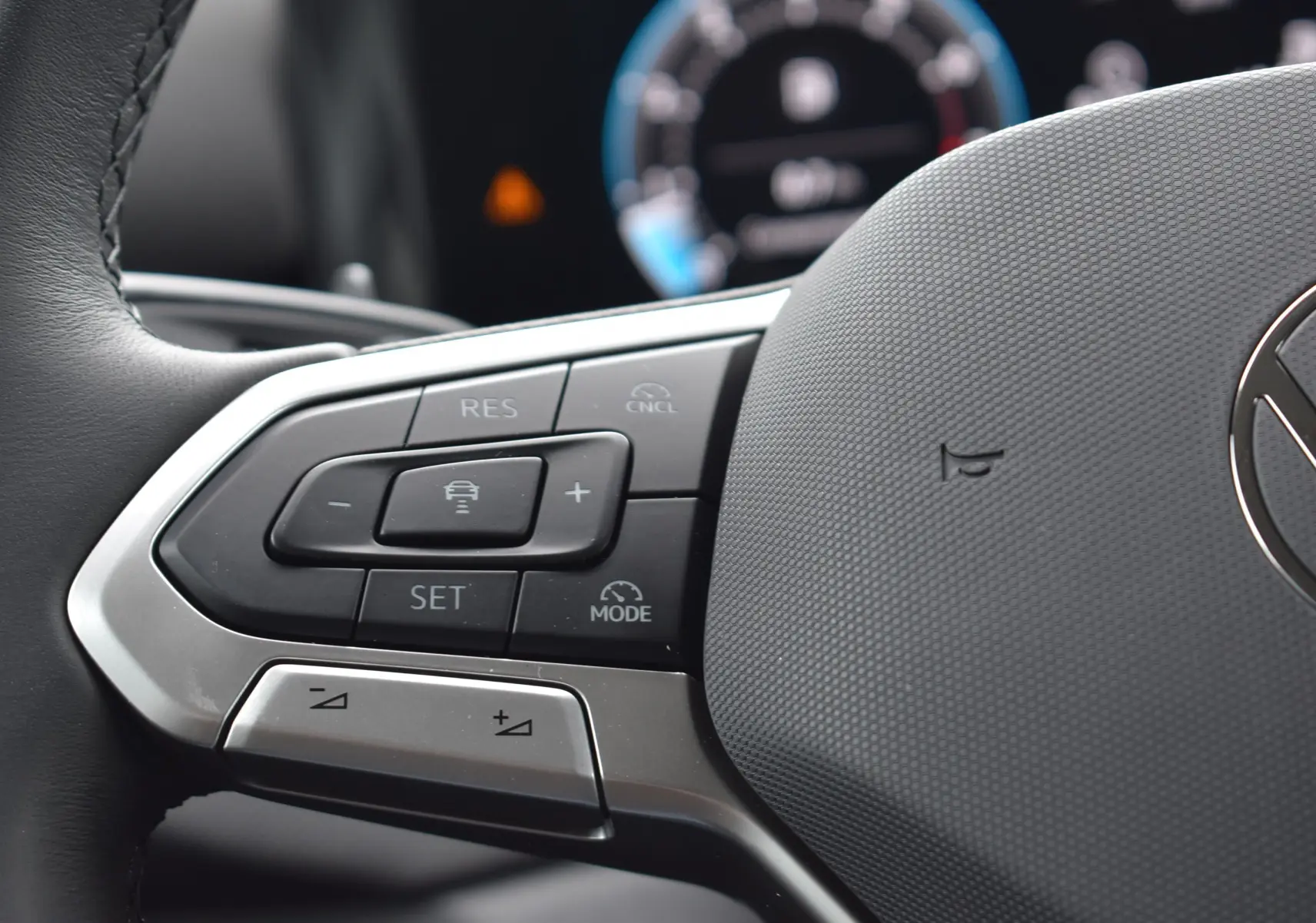 Gros plan sur les commandes multifonctions à gauche du volant du Volkswagen T-Roc blanc 2025.