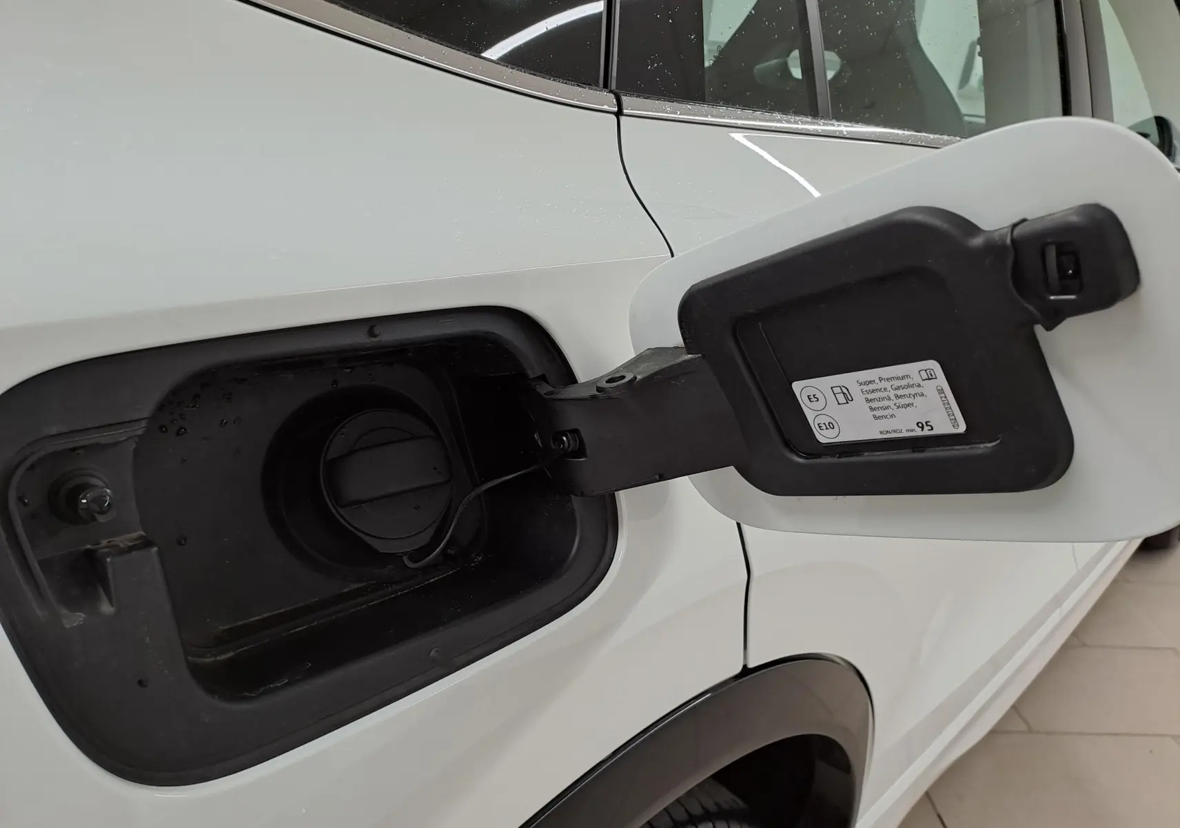 Gros plan sur la trappe à carburant côté gauche d’un Volkswagen Tiguan blanc pur 2025 essence.