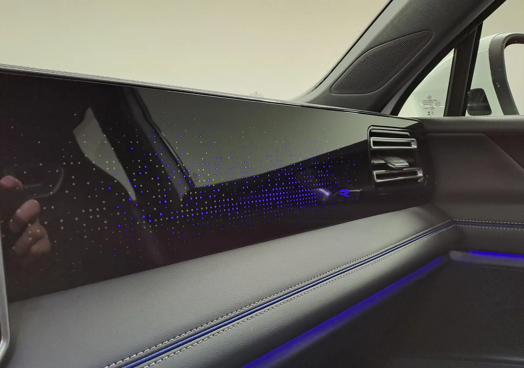 Détail intérieur côté passager du Volkswagen Tiguan 2025 avec éclairage d’ambiance bleu et finition R-Line.