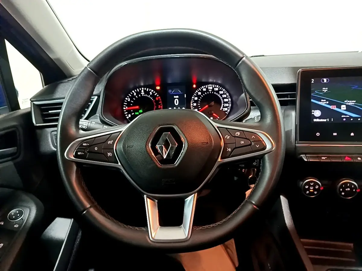Vue intérieure centrée sur le volant cuir multifonctions et tableau de bord avec écran tactile de la Renault Clio Business.