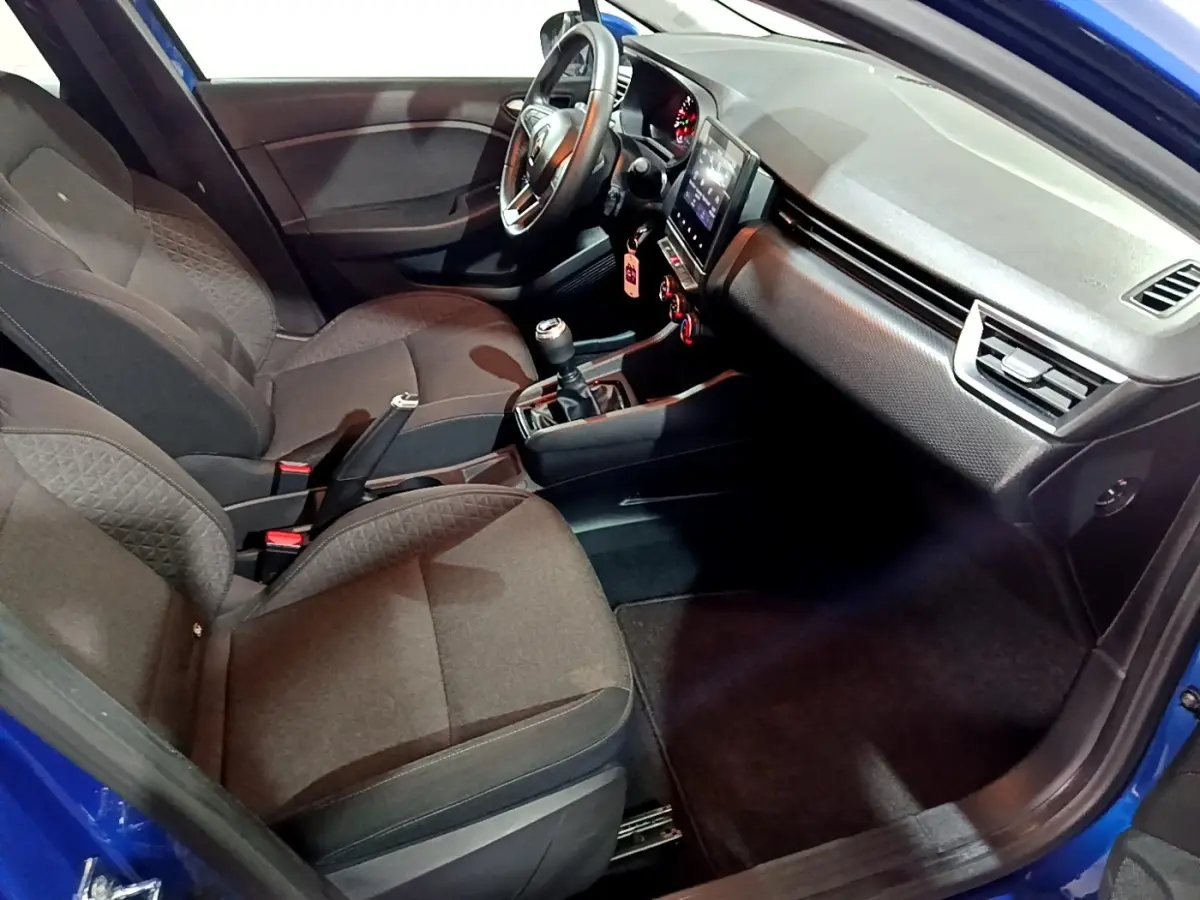 Intérieur de la Renault Clio Business bleu, vue côté conducteur, volant cuir multifonctions et écran tactile central visible.