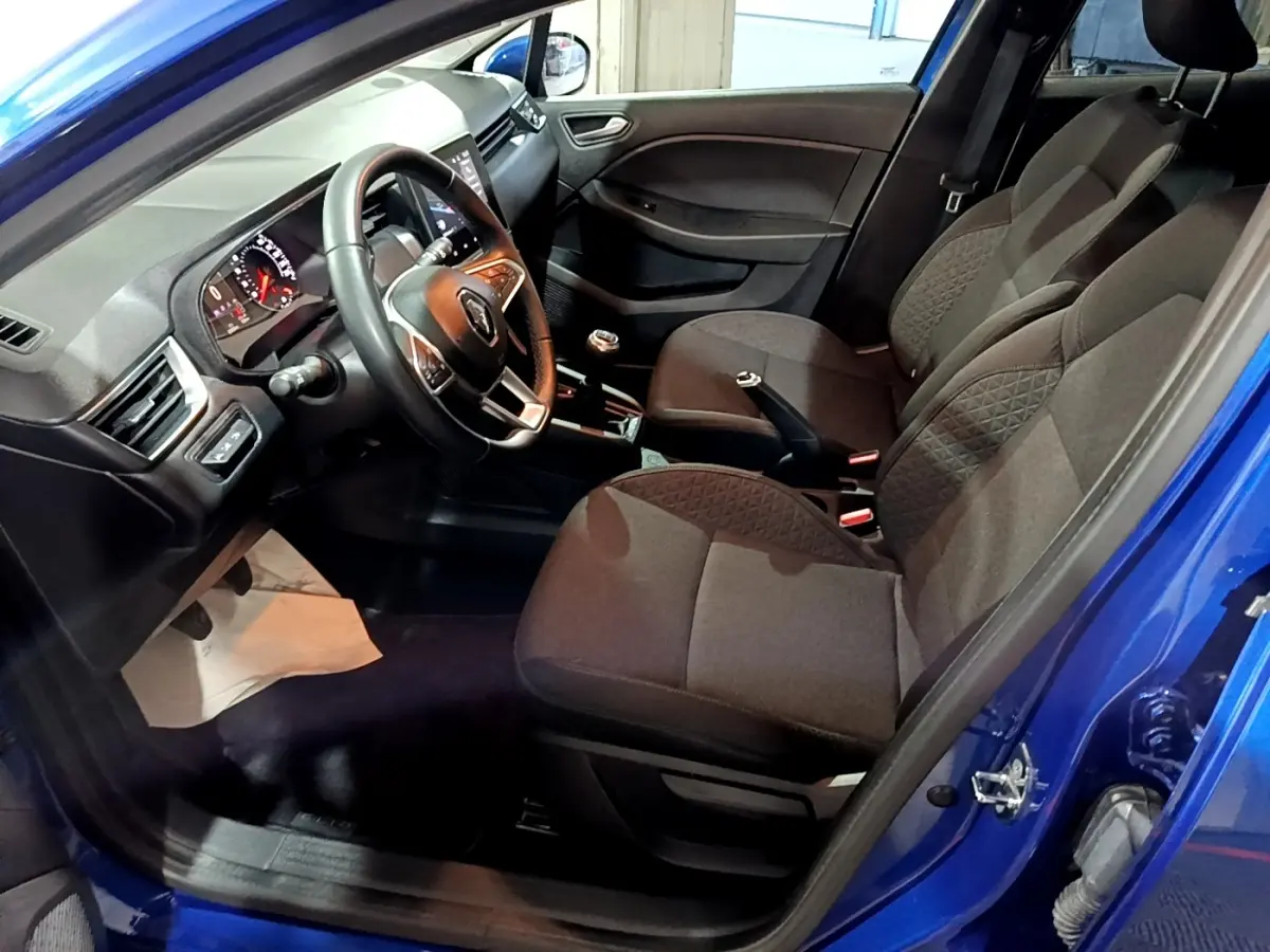 Vue intérieure côté conducteur de la Renault Clio Business bleu 2022, volant cuir multifonctions et sièges tissu gris.