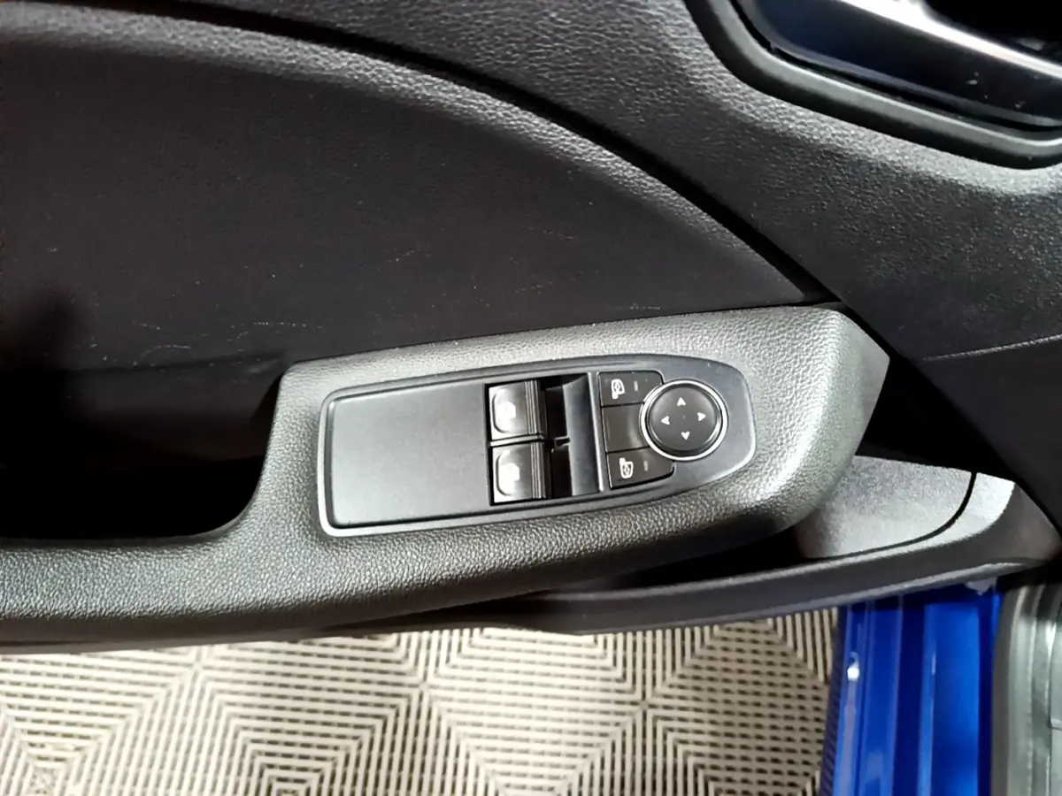 Vue rapprochée de la commande des vitres et rétroviseurs sur la porte côté conducteur d’une Renault Clio bleu 2022.