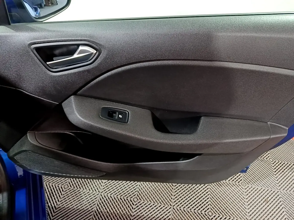 Vue rapprochée de la porte avant gauche noire avec poignée argentée et bouton de commande de vitre d’une Renault Clio bleu.