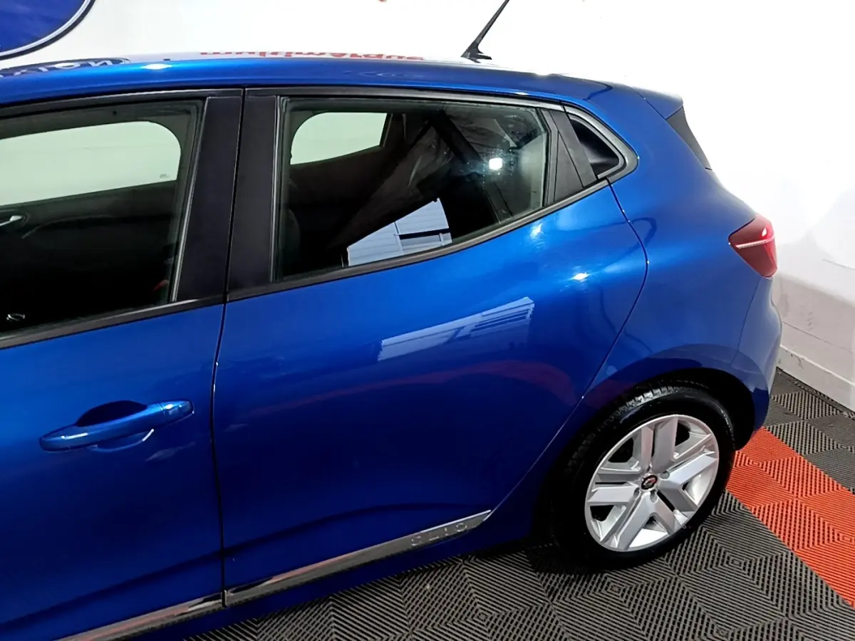 Vue côté gauche arrière d'une Renault Clio Business bleu métallisé avec jantes alliage et poignées de porte intégrées.
