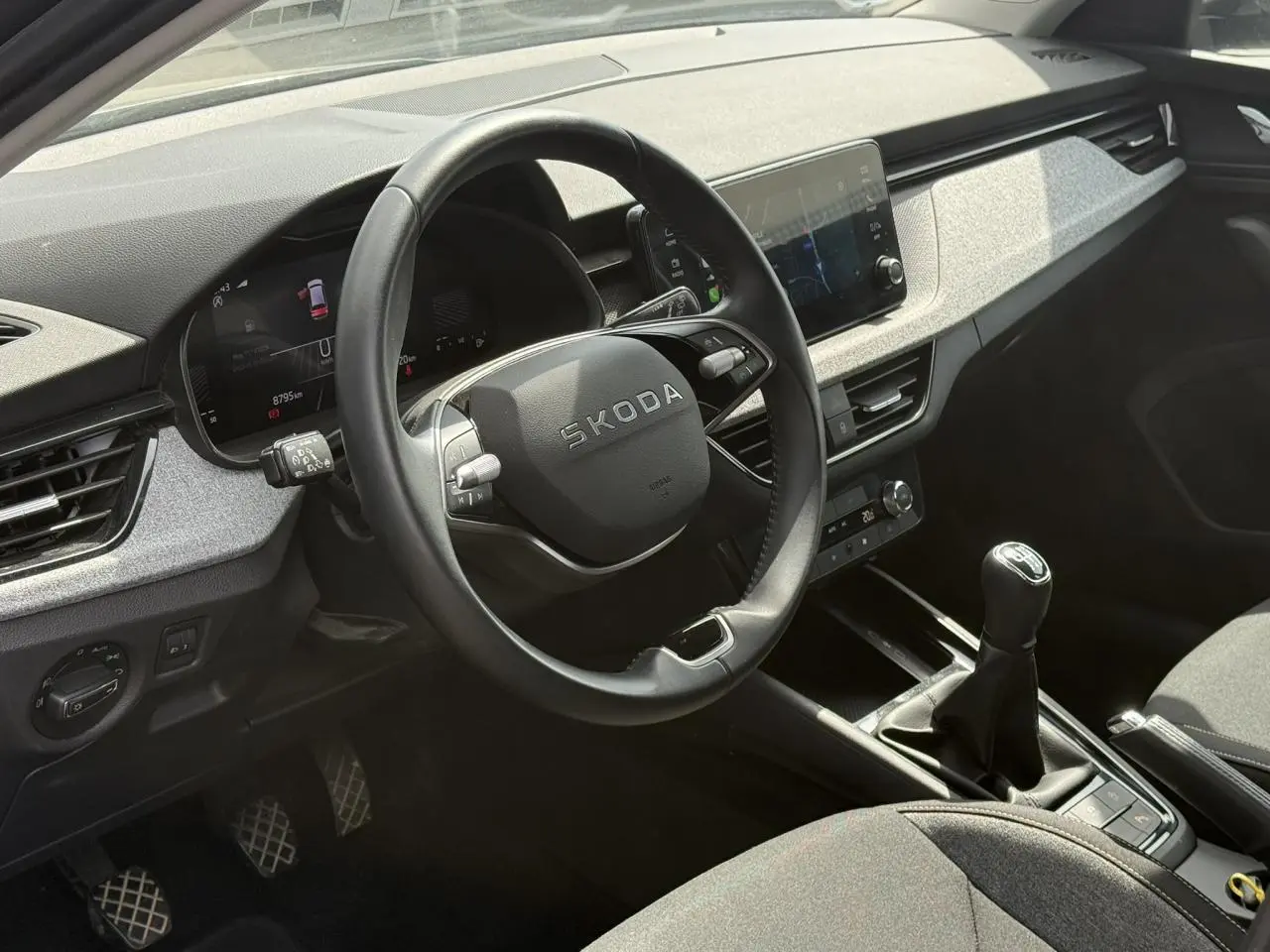 Vue intérieure côté conducteur du Skoda Scala TSI 116 gris graphite, volant cuir multifonctions et levier de vitesses manuel visible.