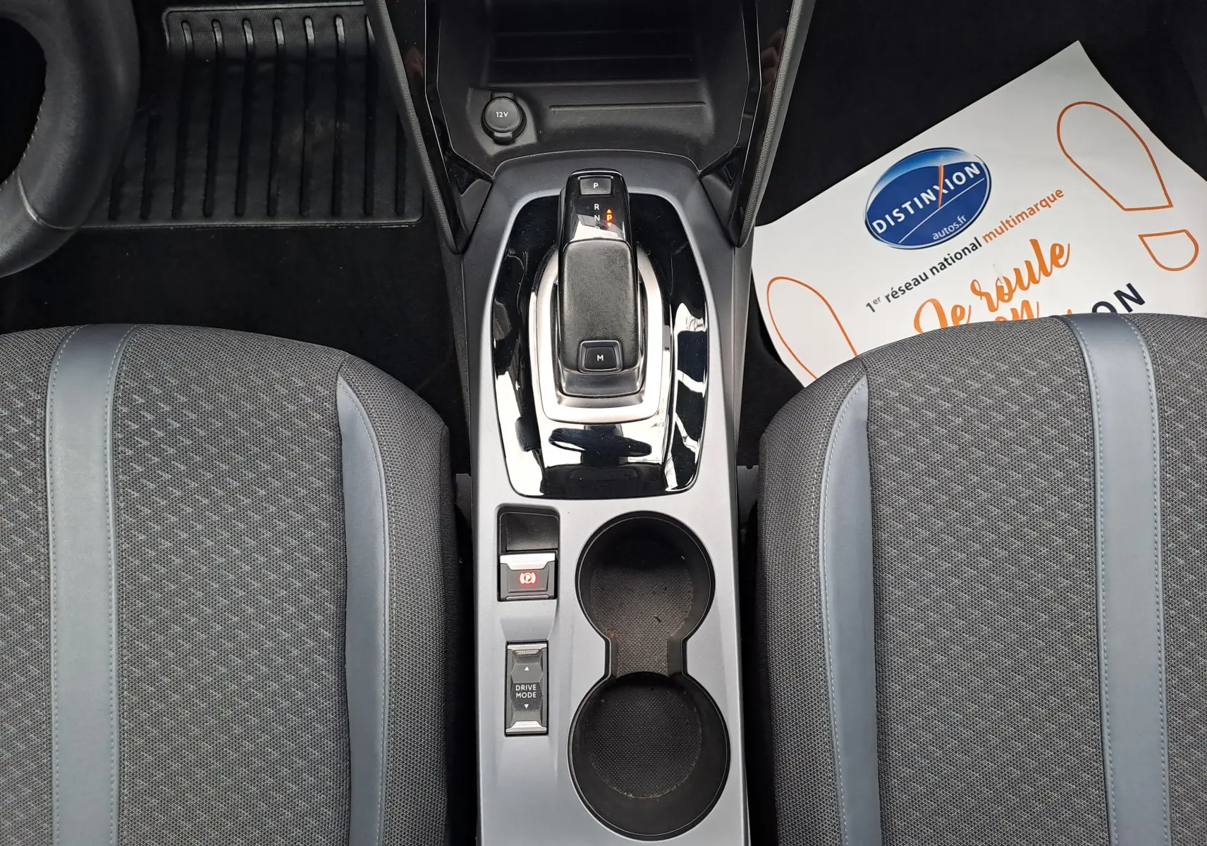 Vue plongeante sur la console centrale du Peugeot 2008 gris Artense, montrant levier de vitesse automatique et sièges tissu gris.
