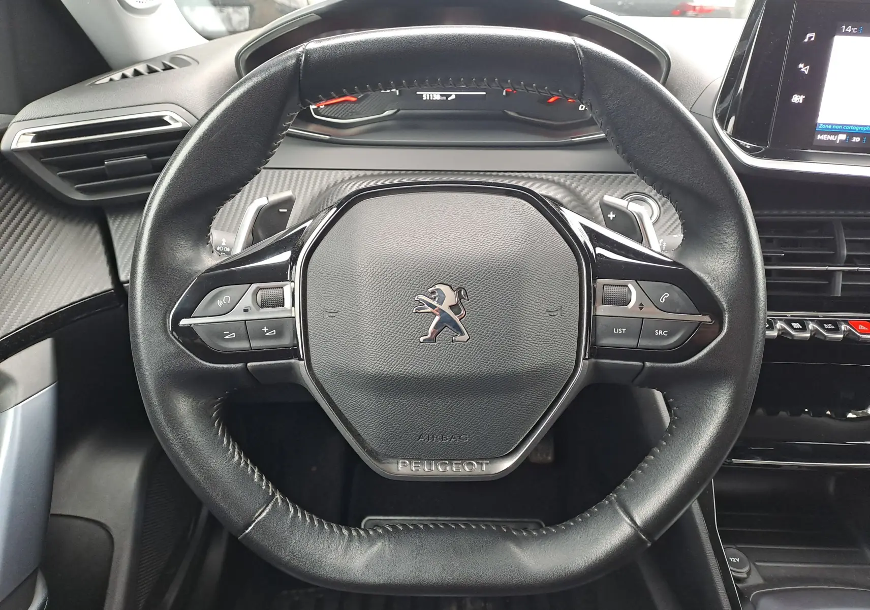 Vue rapprochée du volant cuir noir de la Peugeot 2008 2020 avec commandes intégrées et tableau de bord digital.